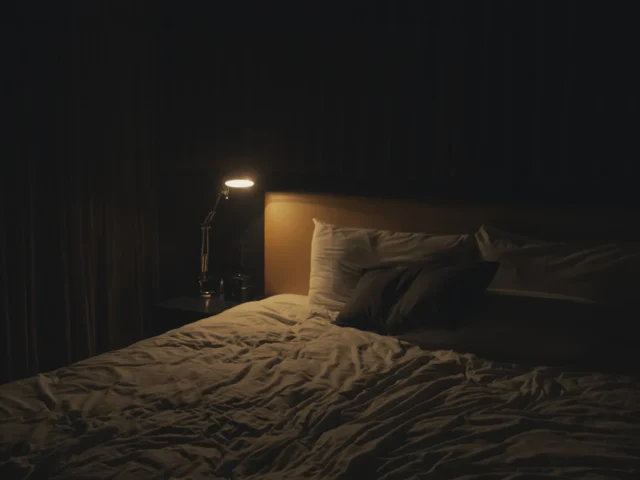 Lámpara encendida junto a una cama en una habitación tenue, imagen relacionada con las pesadillas nocturnas